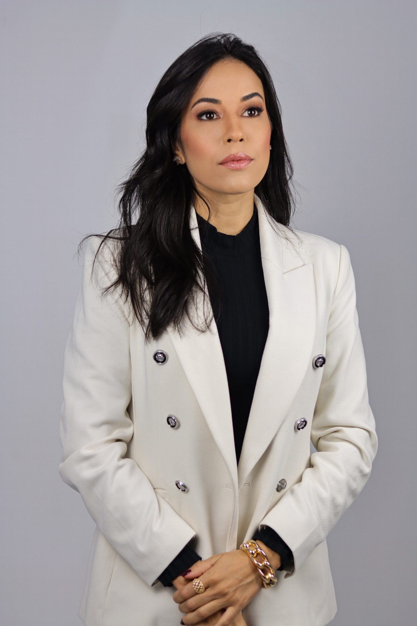 Tayla Assis de blazer off-white, olhando para a câmera